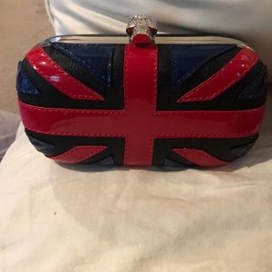 Black clutch with red and navy patent detailing. Rhinestone skull on top